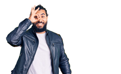 Young arab man wearing casual leather jacket doing ok gesture with hand smiling, eye looking through fingers with happy face.