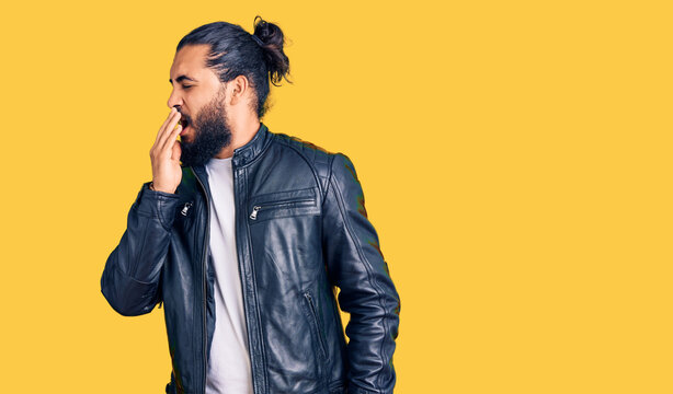 Young arab man wearing casual leather jacket bored yawning tired covering mouth with hand. restless and sleepiness.