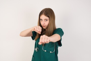 Portrait of strong and determined Female doctor wearing a green scrubs and stethoscope punching air with fist and looking confidently at camera, male struggle, fighting spirit.