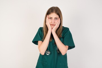 Female doctor wearing a green scrubs and stethoscope. Tired hands covering face, depression and sadness, upset and irritated for problem