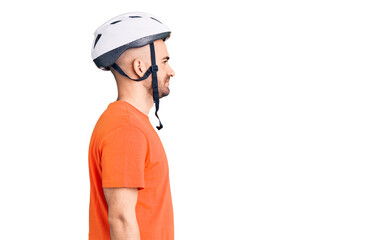Young handsome man wearing bike helmet looking to side, relax profile pose with natural face with confident smile.