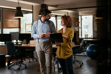 Businesswoman and businessman discussing work in office. Two friends in working together.