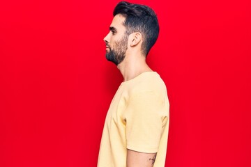 Young handsome man with beard wearing casual t-shirt looking to side, relax profile pose with natural face with confident smile.