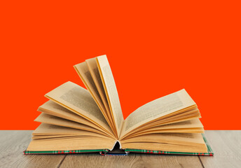 Open book textbook in colorful cover on a orange red background. Back to school distance home education.Quarantine concept of stay home.