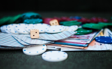 Casino poker chips stack with playing cards, dice and money on green felt background.