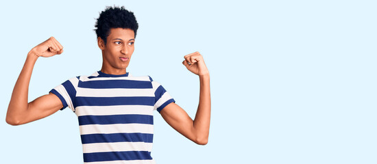 Young african american man wearing casual clothes showing arms muscles smiling proud. fitness concept.