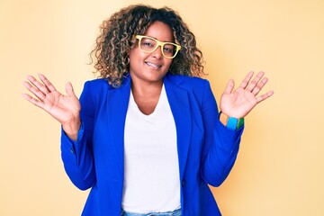 Young african american plus size woman wearing business jacket and glasses clueless and confused...