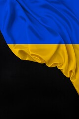 Fototapeta premium silk national flag of Ukraine state is folded in soft folds on a black blank form, the concept of tourism, economy, politics, emigration