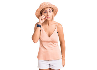Young blonde woman wearing summer hat mouth and lips shut as zip with fingers. secret and silent,...