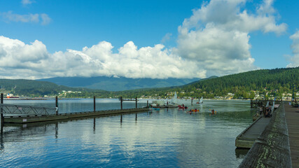 Obraz premium boaters, canoeists and kayakers near jetty at Rocky Point Park, BC, with water, mountain and forest views 