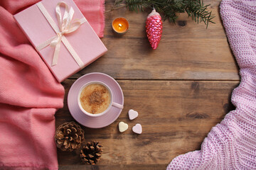 cappuccino with cinnamon in a pink cup, a gift in a box, sweets, candles, cones, Christmas decorations, plaid on an old wooden table, top view, flat, concept cozy home, christmas, copy space