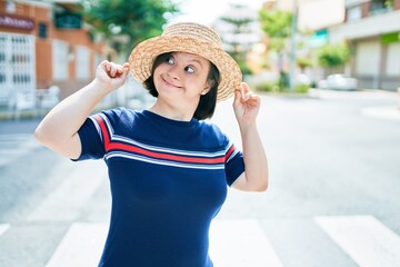 Beautiful brunette woman with down syndrome wearing a summer hat at the town on a sunny day