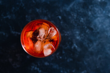 refreshing red spritz cocktail with ice on dark background