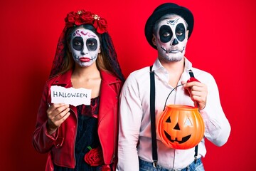 Couple wearing day of the dead costume holding pumpking and halloween paper depressed and worry for distress, crying angry and afraid. sad expression.