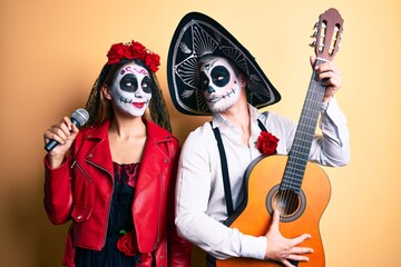 Obraz na płótnie Canvas Couple wearing day of the dead costume playing classical guitar using microphone smiling looking to the side and staring away thinking.