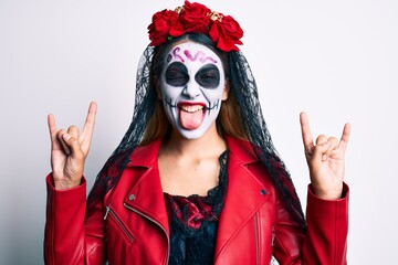 Woman wearing day of the dead costume doing rock and roll gesture with fingers sticking tongue out...
