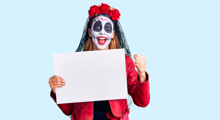 Woman wearing day of the dead costume holding blank empty banner screaming proud, celebrating victory and success very excited with raised arms