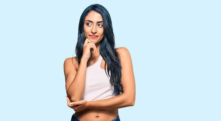 Fototapeta premium Beautiful hispanic woman wearing casual clothes with hand on chin thinking about question, pensive expression. smiling and thoughtful face. doubt concept.