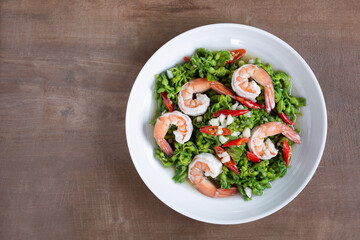 top view of stir fried cowslip creeper with shrimps in a ceramic dish on wooden table. homemade style healthy food concept.