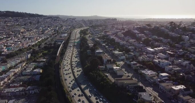 Highway traffic during sunset and cars going in opposite direction. Bart train on the track and muni on the road camera move forward
