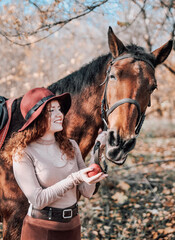 authentic portrait of beautiful redhaired woman with horse outdoors.