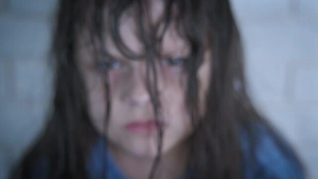 Furious child face. The face of an angry little girl is hidden in her hair.
