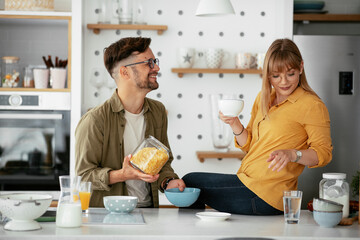 Boyfriend and girlfriend making delicious food. Loving couple eating breakfast together at home.