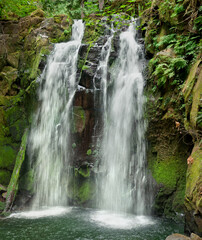 Obraz premium Cascading waterfall with mossy rocks in closeup vertical panoramic view 