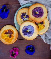 Shortbread cookies with a decor in the form of natural flowers on a dark wooden background
