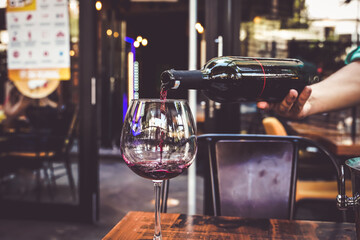 waiter pouring wine in to a wine glass in a cafe restaurant