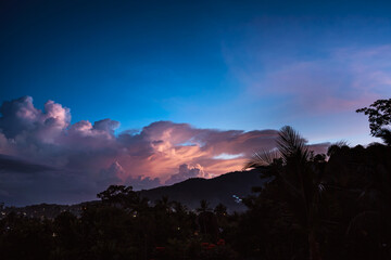 Spectacular sunset sky over valley with trees, city and mountains. View from the top.