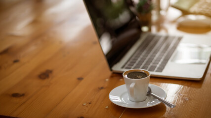 Coffee cups placed next to the laptop on a wooden table in the office.