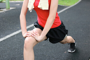 Healthy Asian woman stretching her legs before run in park. Fitness and exercise concept.