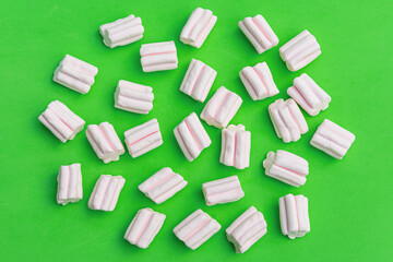 Pattern of pink sweet marshmallows on a green background. Flat top view. Can be used as a background