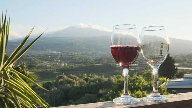 Pouring red wine from a bottle into two glasses on the vineyards in Sicily