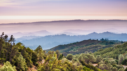 Sunset views in Santa Cruz mountains; Smoke from the nearby burning wildfires, visible in the air and covering the mountain ridges and valleys; South San Francisco Bay Area, California