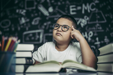 Boys with glasses write books and think in the classroom