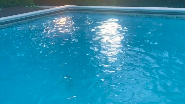 Outdoor swimming pool working and producing water swirls on the surface with sunlight reflection in slow motion