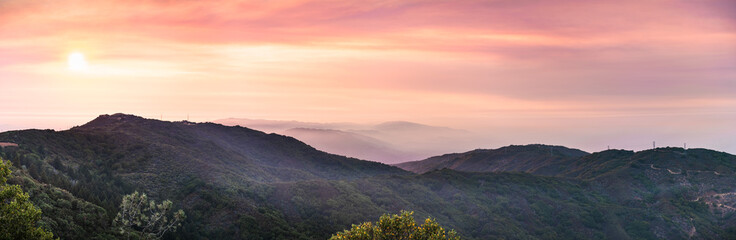 Panoramic sunset views in Santa Cruz mountains; Smoke from the nearby burning wildfires, visible in the air and covering the mountain ridges and valleys; South San Francisco Bay Area, California