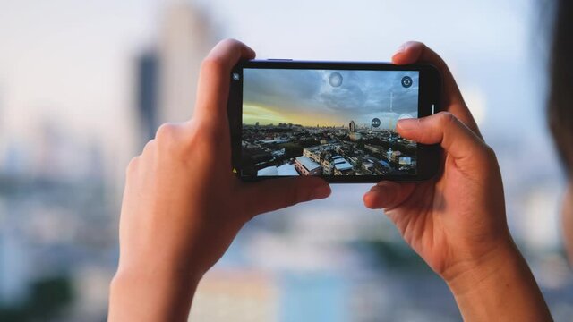 Men take pictures of buildings in the city. At sunrise, he used his phone to record a bird's eye view. Technology concept