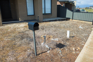  A neglected dry front yard with bare dirt and dead weeds of a residential house in an Australian...