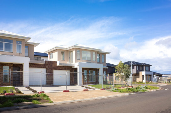 Brand new residential townhouses behind temporary construction fences in an Australian suburb. Concept of real estate development, house for sale, and housing market. Melbourne, VIC Australia.