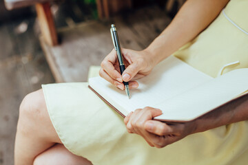 Women writing note book on the table.