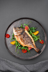 Hot grilled dorado fish with cherry tomatoes, arugula, lemon