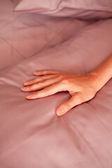 Female hand on the background of a gray bed. Close-up photo
