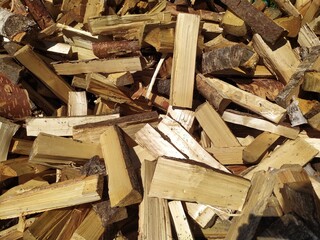 A large pile of chopped wood with an axe in front of the wooden blue house