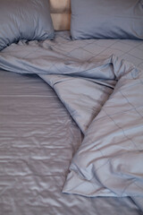 
Unmade empty bed. Bed linen is dark blue.