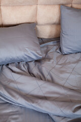 Fototapeta na wymiar Unmade empty bed. Bed linen is dark blue.