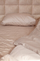 Unmade empty bed. Beige bed linen
