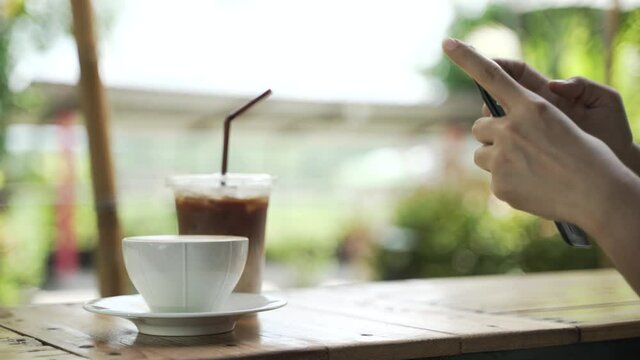 Asian woman shooting picture or take a photo of hot latte coffee with smartphone before drink